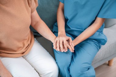 A contented senior woman visited by her personal caregiver and hold each others hands.