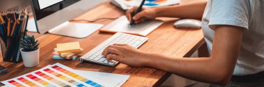Grafik tasarımcısı, modern dijital stüdyo işyerinde profesyonel grafik ekibiyle benzersiz bir tasarım yaparken bilgisayar dizüstü bilgisayar ve grafik çizim kalemi üzerinde çalışır. Panorama çekimi. İnceleyin