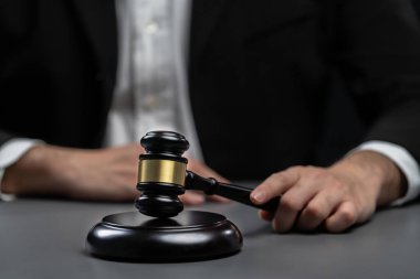 Siyah takım elbiseli bir avukatın elinde tokmak, hukuki adalet ve dürüstlüğün sembolü, hukuk mahkemesinde dengeli ve etik kararın simgesi.