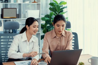 Modern ofis çalışma alanında iş birliği yapan iki genç ofis çalışanı, modern ofis çalışanı olarak profesyonelliklerini sergileyerek, dizüstü bilgisayarda tartışıyorlar ve birlikte çalışıyorlar. Coşkulu.