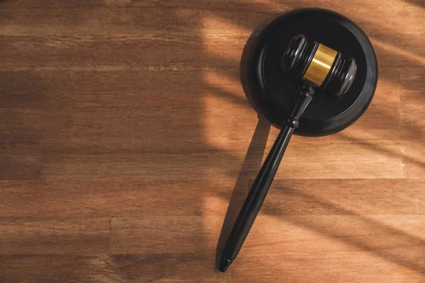 Closeup top view black wooden gavel hammer on wooden office desk background as justice and legal system for lawyer and judge, Legal authority and fairness in trials concept. equility