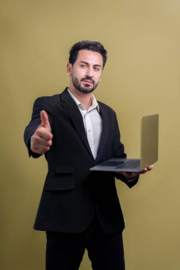 Yenilikçi teknoloji kavramına sahip başarılı bir iş adamı. Başparmaklarıyla poz veriyor, dizüstü bilgisayarını tutuyor ve reklam ya da promosyon için telif alanı arka planında heyecanla gülümsüyor. Coşkulu