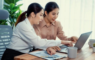 Modern ofis çalışma alanında iş birliği yapan iki genç ofis çalışanı, modern ofis çalışanı olarak profesyonelliklerini sergileyerek, dizüstü bilgisayarda tartışıyorlar ve birlikte çalışıyorlar. Coşkulu.