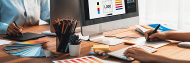 Grafik tasarımcısı, modern dijital stüdyo işyerinde profesyonel grafik ekibiyle benzersiz bir tasarım yaparken bilgisayar dizüstü bilgisayar ve grafik çizim kalemi üzerinde çalışır. Panorama çekimi. İnceleyin