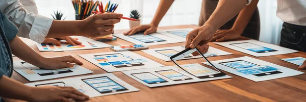 stock image Panorama shot of front-end developer team brainstorming UI and UX designs for mobile app on paper wireframe interface. User interface development team planning for user-friendly UI design. Scrutinize