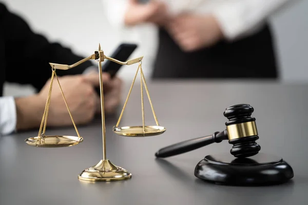Focus shiny golden balanced scale on blurred background of lawyer working on desk at law firm office. Gavel hammer for righteous and equality judgment by lawmaker and attorney. Equilibrium