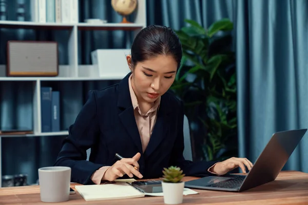 stock image Young asian businesswoman is diligently working and taking notes in her modern office workspace, demonstrating professionalism as attractive and diligent office lady. Enthusiastic