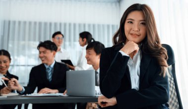 Focus portrait of female manger, businesswoman in the harmony meeting room with blurred of colleagues working together, analyzing financial paper report and dashboard data in background.