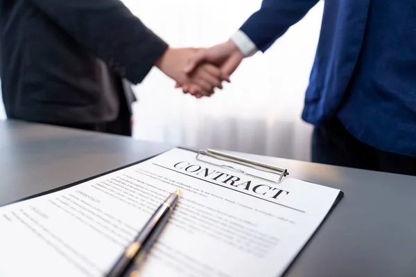 重点关注全景商业合同文件与笔 而两名专业人员握手模糊的背景 意味着成功的谈判和伙伴关系协议与握手 — 图库照片