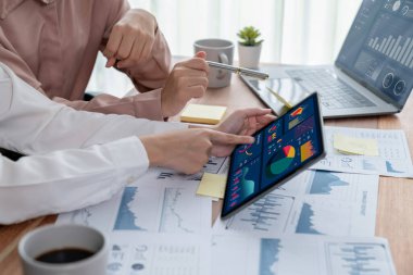 Analist ekip arkadaşı dijital gösterge panelinde finansal verileri tartışır, grafikleri dizüstü bilgisayar ve tablet ekranda analiz eder. Modern ofis pazarlama planlamak için iş zekasını kullanır. Coşkulu.