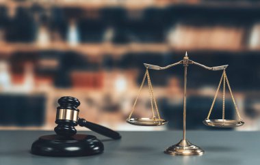 Hukuk firmasında ya da avukatlık bürosunda adalet ve ortak bir hukuki sembol olarak parlak altın dengeli bir ölçek ve ahşap tokmak. Doğruluk ve eşitlik için teraziyi tartın. Eşitlik