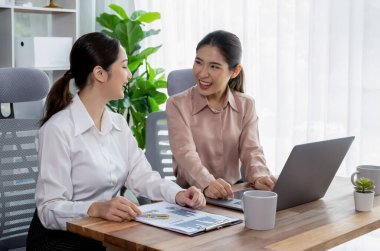 Modern ofis çalışma alanında iş birliği yapan iki genç ofis çalışanı, modern ofis çalışanı olarak profesyonelliklerini sergileyerek, dizüstü bilgisayarda tartışıyorlar ve birlikte çalışıyorlar. Coşkulu.