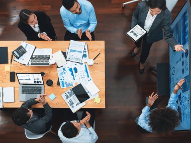Modern toplantı odasındaki TV ekranında veri analizi paneliyle üst görünüm iş sunumu. İş adamlarının iş pazarlama stratejisini planlamak için beyin fırtınası yapması ya da birlikte çalışması. Uyum