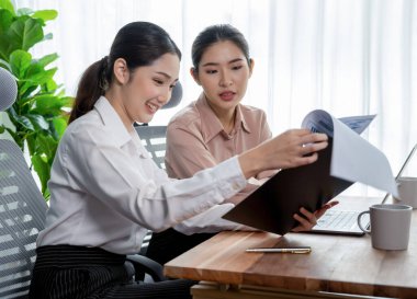 Modern ofis çalışma alanında iş birliği yapan iki genç ofis çalışanı, modern ofis çalışanı olarak profesyonelliklerini sergileyerek, dizüstü bilgisayarda tartışıyorlar ve birlikte çalışıyorlar. Coşkulu.