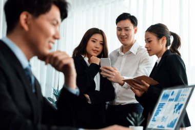 Harmony in office concept as business people analyzing dashboard paper together in workplace. Young colleagues give ideas at manager desk for discussion or strategy planning about project.