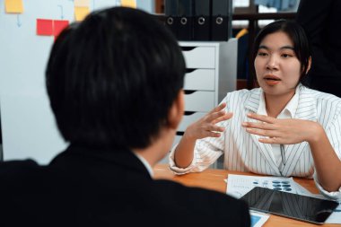 Manager advising guiding younger colleague with tablet in workplace. Couple businesspeople in formal wear working together on financial strategy as concept of teamwork and harmony in office.