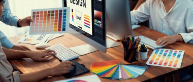 Grafik tasarımcısı, modern dijital stüdyo işyerinde profesyonel grafik ekibiyle benzersiz bir tasarım yaparken bilgisayar dizüstü bilgisayar ve grafik çizim kalemi üzerinde çalışır. Panorama çekimi. İnceleyin