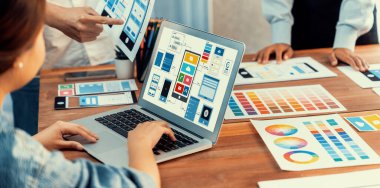 Dizüstü bilgisayar ekranında mobil uygulama için UI ve UX tasarımları tasarlayan ön uç geliştirici ekibin panorama görüntüsü. Kullanıcı dostu UI tasarımı için kullanıcı arayüzü geliştirme ekibi planlama. İnceleyin