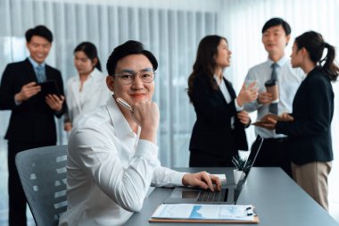 Portrait of focus young successful confident male manager, executive wearing business wear in harmony office arm crossed with blurred meeting background of colleagues, office worker.