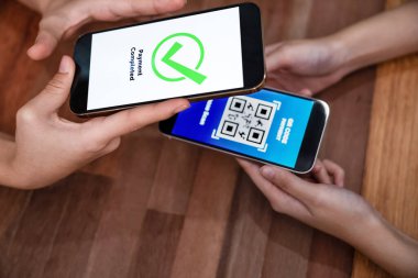 QR kodu parasız ödeme taraması için ekranda gösterilir. Kapalı eller, mobil uygulamadan elektronik işlem yoluyla para aktarmak için akıllı telefonu tutuyor. Hızlı ödeme için barkod teknolojisi. Coşkulu.