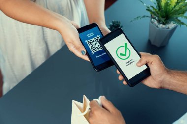 Parasız ödeme taraması için QR kodu ekranda görüntülendi. Kapalı eller, mobil uygulamadan elektronik işlem yoluyla para aktarmak için akıllı telefonu tutuyor. Hızlı ödeme için barkod teknolojisi. Coşkulu
