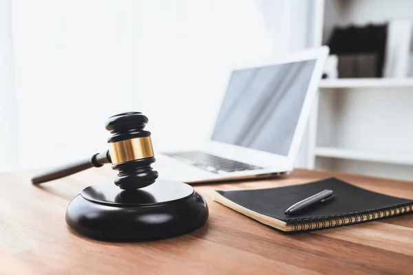 stock image Closeup wooden gavel hammer with laptop and book and pen on desk on wooden office table background as justice legal system for lawyer and judge, Symbolize authority and fairness in trial. equility
