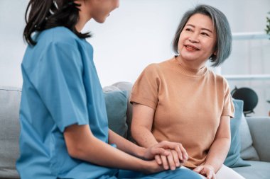 A contented senior woman visited by her personal caregiver and hold each others hands.