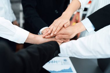 Top view closeup business team of suit-clad businesspeople join hand stack together. Colleague collaborate and work together to promote harmony and teamwork concept in office workplace.