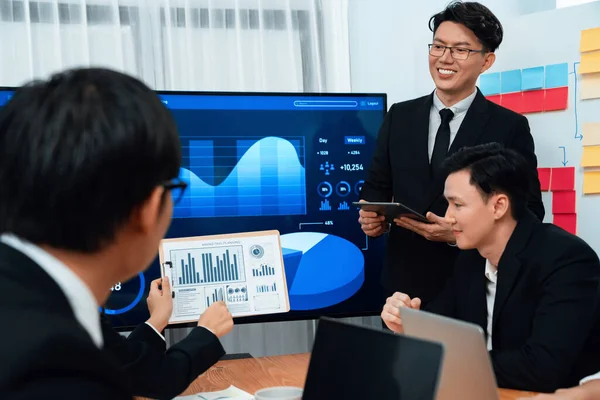 stock image Harmony group businesspeople in meeting room during presentation with dashboard BI financial data displayed on screen, motivated employee raising hand asking question as productive teamwork concept.