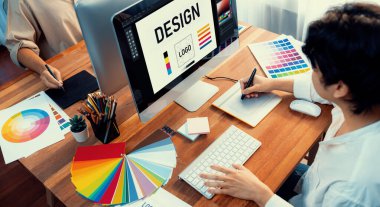Grafik tasarımcısı, modern dijital stüdyo işyerinde profesyonel grafik ekibiyle benzersiz bir tasarım yaparken bilgisayar dizüstü bilgisayar ve grafik çizim kalemi üzerinde çalışır. Panorama çekimi. İnceleyin