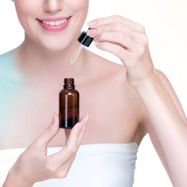 Closeup personable portrait of beautiful woman applying essential oil bottle for skincare product. Cannabis extracted CBD oil dropper for treatment and cannabinoids concept in isolated background.