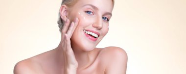 Personable beautiful perfect clean skin soft makeup woman finger applying moisturizer cream on her face under contour eye for anti aging wrinkle. Facial skin rejuvenation in isolated background.