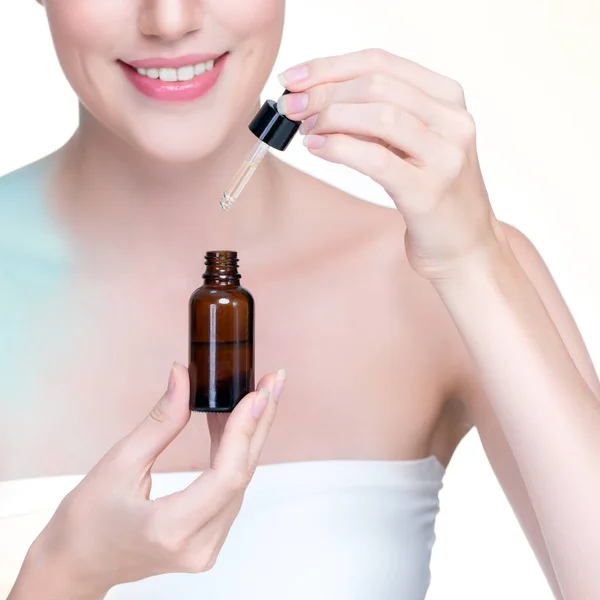 stock image Closeup personable portrait of beautiful woman applying essential oil bottle for skincare product. Cannabis extracted CBD oil dropper for treatment and cannabinoids concept in isolated background.