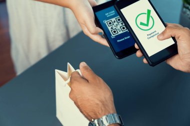 Parasız ödeme taraması için QR kodu ekranda görüntülendi. Kapalı eller, mobil uygulamadan elektronik işlem yoluyla para aktarmak için akıllı telefonu tutuyor. Hızlı ödeme için barkod teknolojisi. Coşkulu
