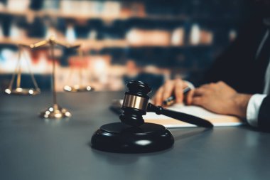 Tahta tokmak çekicini kütüphanede çalışan ya da okuyan avukatın bulanık arka planına odakla. Kanun yapıcı ve avukatın adil ve adil yargılaması için meşru çekiç. Eşitlik