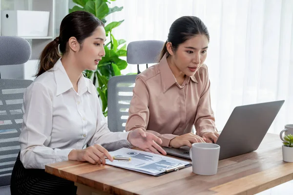 Modern ofis çalışma alanında iş birliği yapan iki genç ofis çalışanı, modern ofis çalışanı olarak profesyonelliklerini sergileyerek, dizüstü bilgisayarda tartışıyorlar ve birlikte çalışıyorlar. Coşkulu.