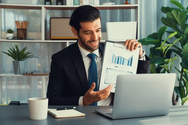 Siyah takım elbiseli profesyonel işadamı, online toplantı sırasında dizüstü bilgisayarla finansal veri ya da BI belgesi sunuyor. Etkili uzaktan çalışmanın sanal toplantı sunumuyla uzaktan çalışma konsepti. Coşkulu