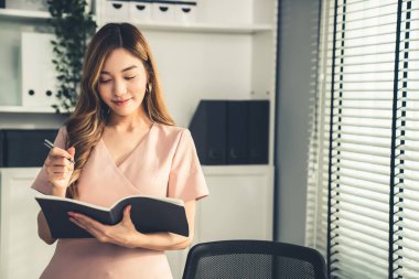 Young competent office lady, intern, secretary holding a log in office room. Concept of various career for office working. Concept of diverse office careers.