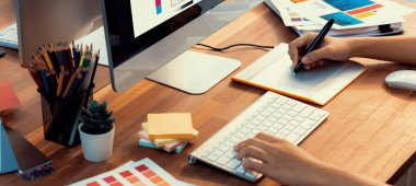 Grafik tasarımcısı, modern dijital stüdyo işyerinde profesyonel grafik ekibiyle benzersiz bir tasarım yaparken bilgisayar dizüstü bilgisayar ve grafik çizim kalemi üzerinde çalışır. Panorama çekimi. İnceleyin