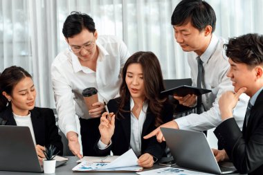 Harmony in office concept as business people analyzing dashboard paper together in workplace. Young colleagues give ideas at manager desk for discussion or strategy planning about project.