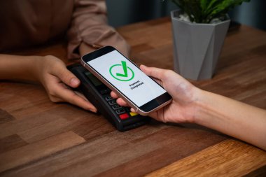QR kodu parasız ödeme taraması için ekranda gösterilir. Kapalı eller, mobil uygulamadan elektronik işlem yoluyla para aktarmak için akıllı telefonu tutuyor. Hızlı ödeme için barkod teknolojisi. Coşkulu.