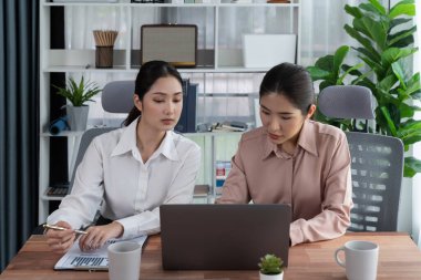 Modern ofis çalışma alanında iş birliği yapan iki genç ofis çalışanı, modern ofis çalışanı olarak profesyonelliklerini sergileyerek, dizüstü bilgisayarda tartışıyorlar ve birlikte çalışıyorlar. Coşkulu.