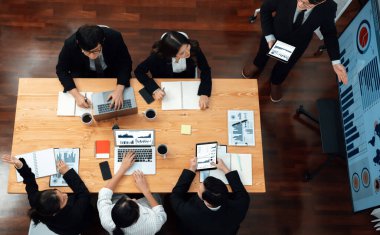 Top view manager or office worker give presentation in harmony conference room to business colleague, BI data dashboard on screen and pile of financial analyzed data reports on meeting table.
