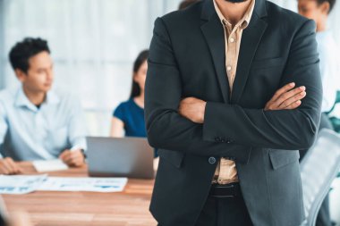 İş adamı, toplantı odasının arka planında çeşitli iş arkadaşlarıyla güven içinde poz veriyor. Çok kültürlü ekip iş başarısı için birlikte çalışır. Modern iş adamı portresi. Uyum