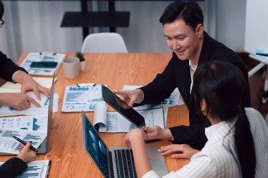 Harmony in office concept as business people analyzing dashboard paper together in workplace. Young colleagues give ideas at manager desk for discussion or strategy planning about project.