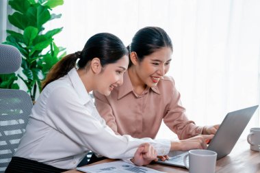 Modern ofis çalışma alanında iş birliği yapan iki genç ofis çalışanı, modern ofis çalışanı olarak profesyonelliklerini sergileyerek, dizüstü bilgisayarda tartışıyorlar ve birlikte çalışıyorlar. Coşkulu.