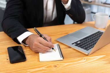 Modern ofis masasındaki modern profesyonel iş adamı çalışmak ve notlar yazmak için dizüstü bilgisayar kullanıyor. Ofisinde bilgisayar defteri üzerinde çalışan çalışkan bir ofis çalışanı. coşkulu