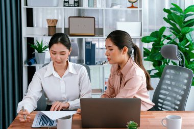 Modern ofis çalışma alanında iş birliği yapan iki genç ofis çalışanı, modern ofis çalışanı olarak profesyonelliklerini sergileyerek, dizüstü bilgisayarda tartışıyorlar ve birlikte çalışıyorlar. Coşkulu.