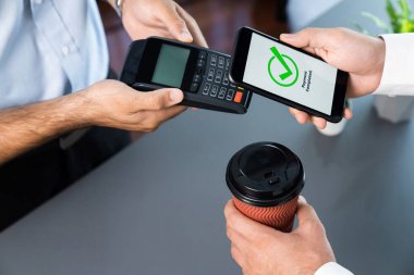 NFC QR kod cihazı ile el ele tutuşan akıllı telefon, hızlı dijital işlemler için temas kurulamayan ödeme kodlarını tarıyor. Modern yaşam tarzı ödeme teknolojisi için cep telefonundaki online bankacılık uygulaması. coşkulu