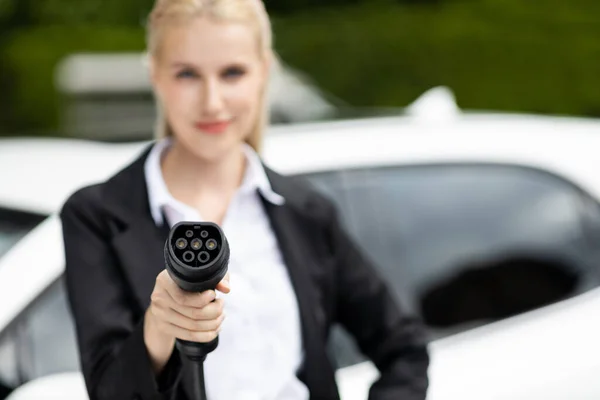 stock image Blur closeup businesswoman hand holding and pointing an EV plug at camera for electric vehicle as progressive idea of alternative sustainable clean and green energy for environmental concern.